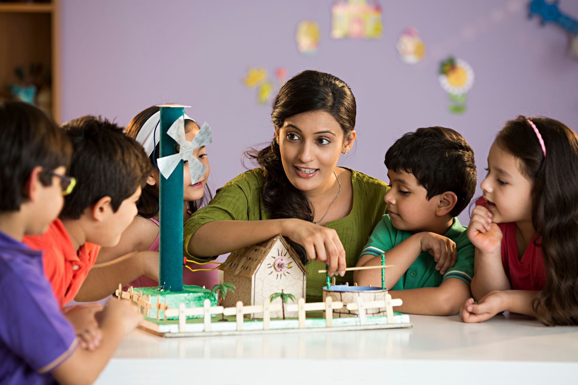 a child working on robots and teacher teaching to her